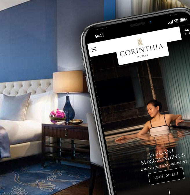 An image of the Corinthia Hotels website page on the screen of a mobile phone, with a blue hotel suite in the background.