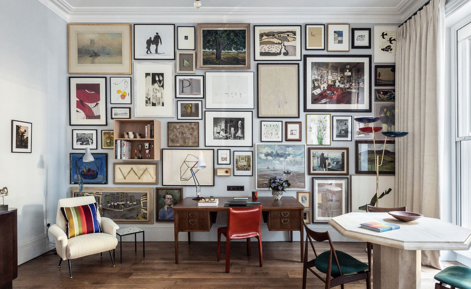 A wall filled with framed paintings inside the Sir Paul Smith Suite at Brown's Hotel
